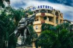 Statue with an umbrella stands in front of the Astoria Hotel, surrounded by lush palm trees in Plaza de Cayzedo, Cali, Valle del Cauca.