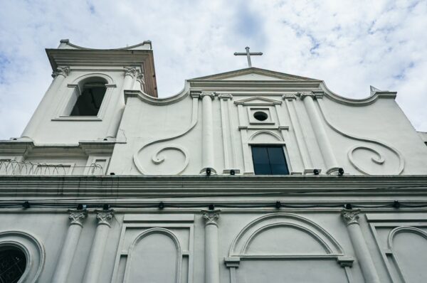 White colonial architecture features intricate detailing on the facade of a church in San Antonio, Cali, Valle del Cauca, Colombia.