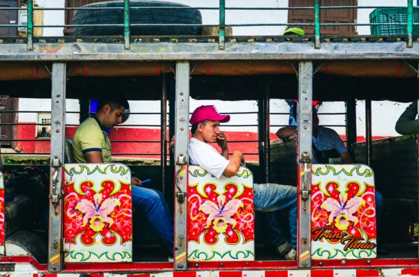 Colorful seats adorn the bus as passengers relax inside, showcasing vibrant patterns typical in Cauca, Colombia.
