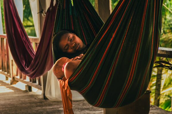 Relaxing in colorful hammocks, a woman enjoys a peaceful moment in Ladrilleros, Valle del Cauca, Colombia, surrounded by greenery.