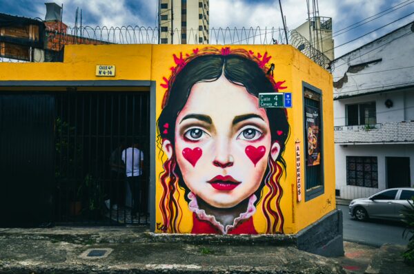 Vibrant mural featuring a girl with heart-shaped designs on a yellow wall in San Antonio, Cali, Valle del Cauca, Colombia.