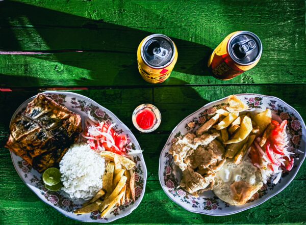 Delicious traditional Colombian meals served on decorative plates, accompanied by drinks, set against a vibrant green table.