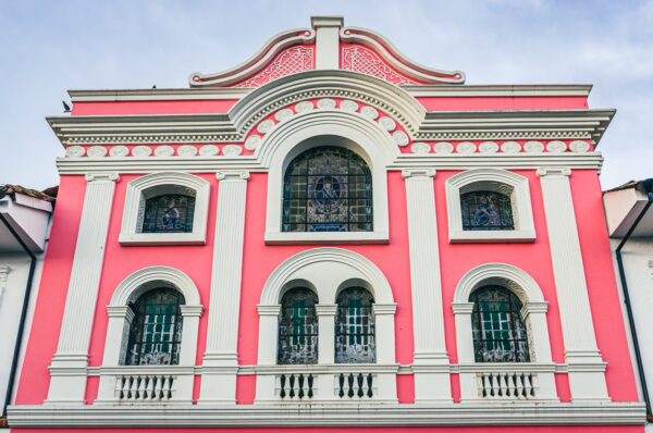Pink colonial architecture with ornate details and arched windows stands out in Popayán, Cauca, Colombia, under a clear sky.