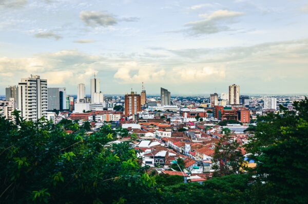Cali's skyline showcases modern buildings amidst lush greenery, with a mix of colorful rooftops below at Colina de San Antonio.