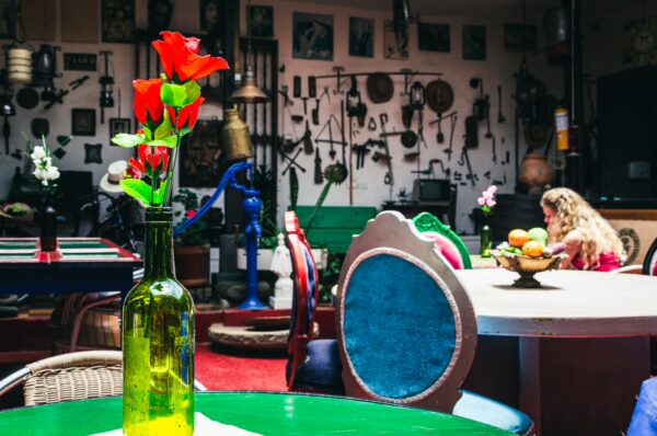 Brightly colored flowers in a green bottle sit on a table, surrounded by eclectic decor and a cozy café atmosphere at Molino Dorado, Cauca, Colombia.