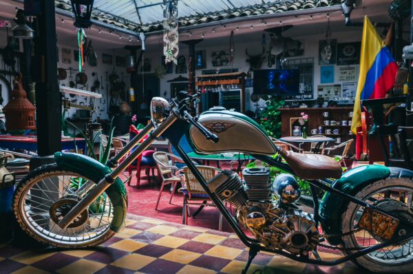 Vintage motorcycle with teal and silver accents showcased in a cozy café setting, a glimpse of Colombian culture in Cauca.