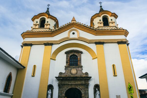 Iglesia San José features a striking yellow and white facade, with ornate details and twin bell towers in Popayán, Cauca, Colombia.