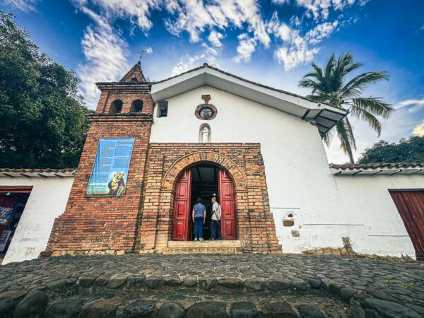 Colina de San Antonio features a charming brick church with red doors, surrounded by lush greenery and a bright blue sky in Cali, Valle del Cauca.
