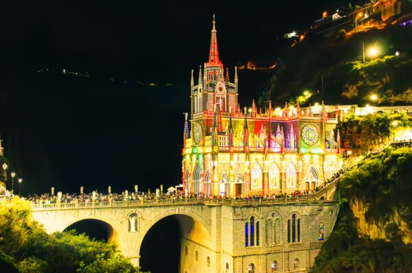 Las Lajas Sanctuary illuminated at night, featuring vibrant colors and stunning architecture in Narino, Colombia.