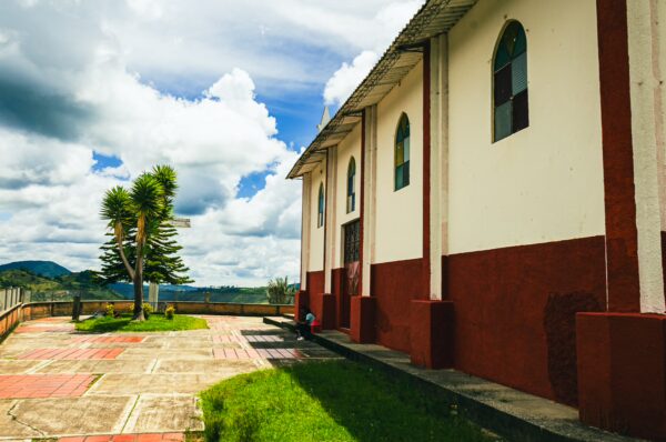 Belen Hill features a white and red church with arched windows and green grass under a blue sky in Silva, Cauca, Colombia.
