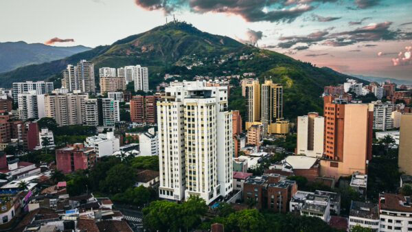 Vibrant cityscape showing modern buildings with the lush Colina de San Antonio mountain in the background, Cali, Valle del Cauca.
