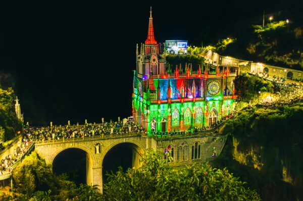 Las Lajas Sanctuary illuminated at night with vibrant colors, showcasing its stunning architecture in Nariño, Colombia.