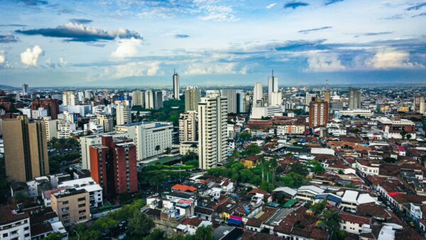 Vibrant skyline featuring modern buildings and lush greenery in Cali, Valle del Cauca, Colombia, under a blue sky.