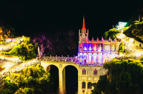 Las Lajas Sanctuary illuminated at night, showcasing vibrant colors against the dark backdrop of the canyon in Narino, Colombia.