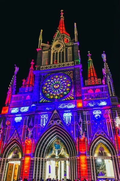 Illuminated Las Lajas Sanctuary in Nariño, Colombia, showcases vibrant colors and intricate gothic architecture at night.