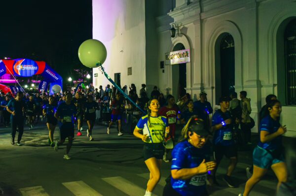 Vibrant night scene of a running event with participants in blue shirts, set in the streets of Popayán, Cauca, Colombia.