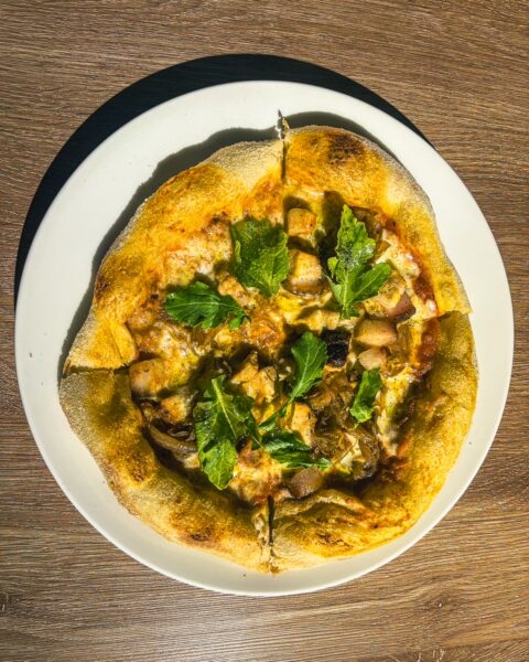 Delicious pizza topped with fresh herbs and melty cheese served on a white plate, vibrant and inviting in Popayán, Cauca, Colombia.
