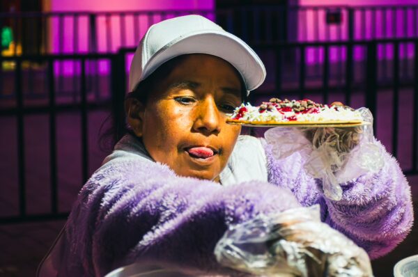 Street vendor serving colorful snacks in Parque Caldas, Popayán, Cauca, showcasing vibrant local cuisine and lively atmosphere.