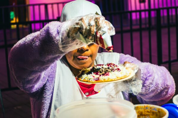 A woman in gloves expertly dressing a plate of colorful food at Parque Caldas, Popayán, Cauca, Colombia.