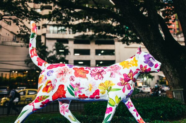 Vibrant, flower-adorned cat statue at Parque del Gato de Tejada, showcasing colorful art in Cali, Valle del Cauca, Colombia.