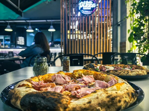 Delicious pizza topped with ham, displayed on a table at La Bella Pizza in Cali, Valle del Cauca, Colombia, with a cozy ambiance.