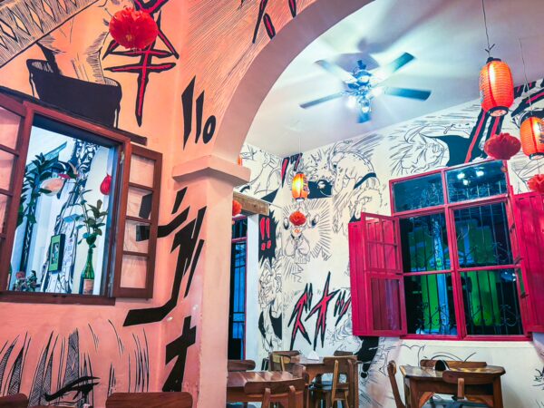 Vibrant interior featuring artistic wall murals, colorful lanterns, and wooden tables in a Japanese ramen restaurant in Cali, Valle del Cauca.