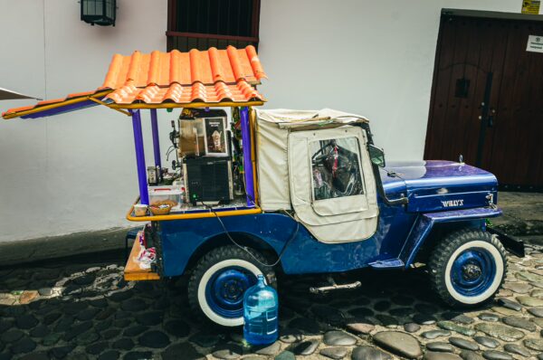 Colorful jeep with a canopy selling drinks, parked on cobblestone streets in Popayán, Cauca, Colombia.