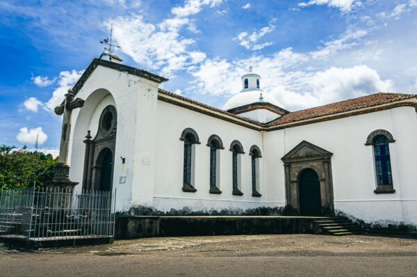 White colonial architecture features arched windows and a dome under a blue sky at Santuario de Belén in Popayán, Cauca, Colombia.