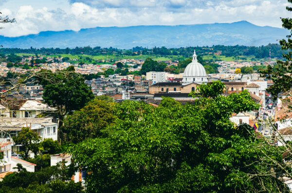 A panoramic view showcasing lush greenery and the distinctive dome of Santuario de Belén in Popayán, Cauca, Colombia.