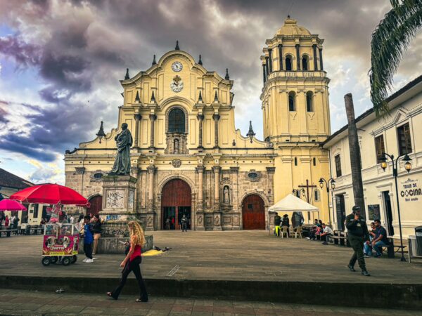 Beautiful church with yellow façade under dramatic skies, surrounded by vibrant street life in Popayán, Cauca, Colombia.