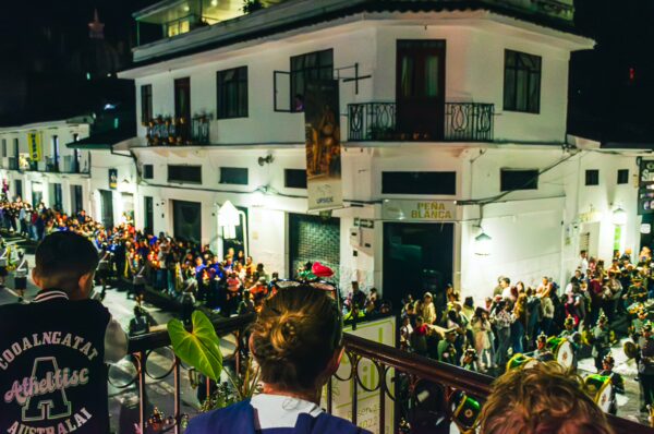Vibrant street scene at night in Popayán, Cauca, Colombia, with crowds gathered outside a historic building.
