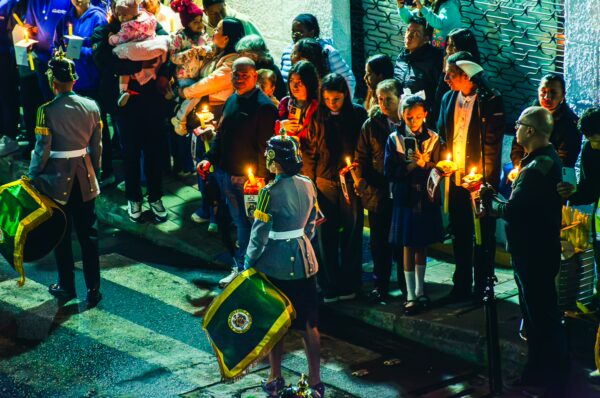 Candlelight procession in Popayán, Cauca, Colombia, featuring participants in traditional attire and vibrant surroundings.