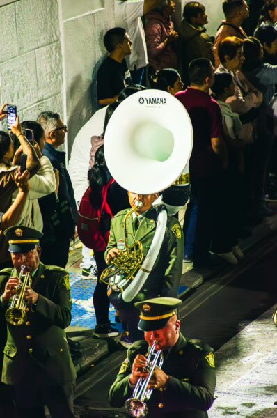 A lively scene in Popayán, Colombia, showcasing musicians in uniform performing, surrounded by an engaged crowd at night.