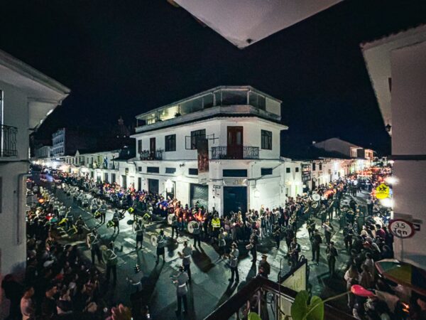 Festive crowd gathered in the streets of Popayán, Cauca, Colombia, illuminated by night lights during a vibrant celebration.