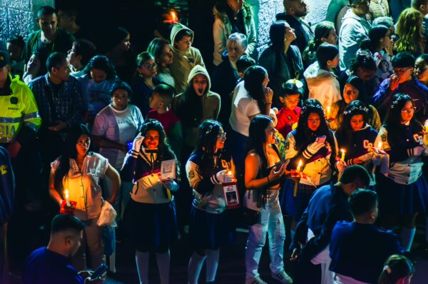 Vibrant crowd holding candles during a celebration in Popayán, Cauca, Colombia, illuminated by festive lights.