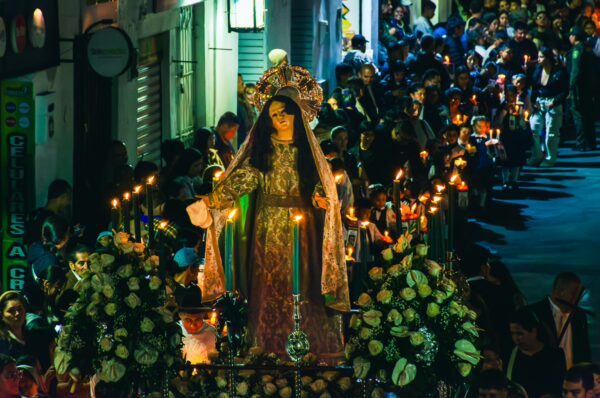 Vibrant procession in Popayán, Colombia, featuring a decorated statue surrounded by candles and flowers during a celebration.