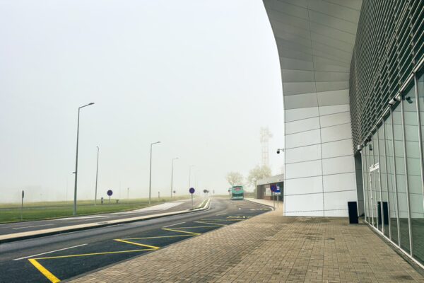 Fog envelops the approach to Craiova Airport, with empty roads and modern architecture visible in the hazy atmosphere.
