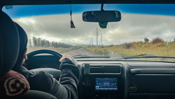 Driving through Cotopaxi National Park, Ecuador, with a view of the winding road ahead and overcast skies.