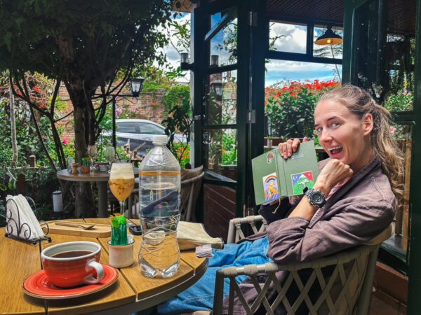 A woman enjoying a coffee and snacks at a cozy café with lush greenery and a scenic view in Ibarra, Ecuador.