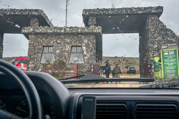 Stone entrance with a weathered texture, showcasing Chimborazo Volcano's national park signage in Ecuador. Rain-soaked atmosphere enriches the scene.