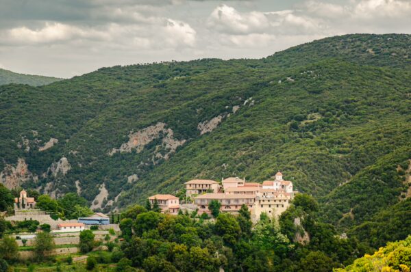 Serene landscape featuring a historic building nestled among lush green hills in Vytina, a picturesque village in Nymfasia, Arcadia, Greece.