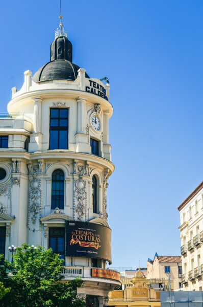 Teatro Calderón showcases elegant architecture and a bright blue sky in Madrid, Spain, with intricate details and signage.