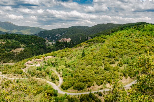 Scenic view of lush green hills and winding roads leading to Nymfasia, surrounded by the mountains of Arcadia, Greece.