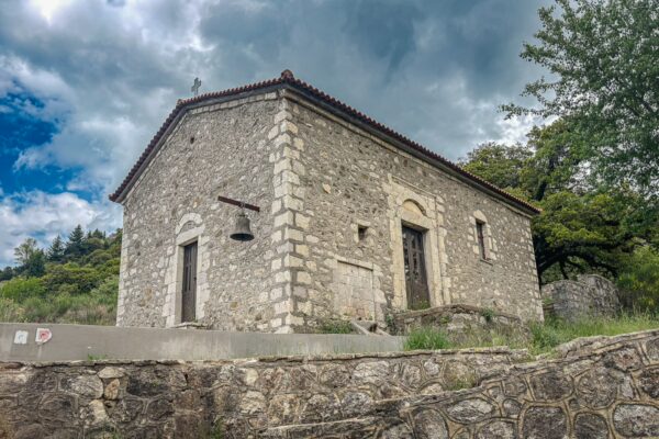 Traditional stone church nestled in lush greenery under a cloudy sky in Zygovisti, Elati Menalon, Arcadia, Greece.