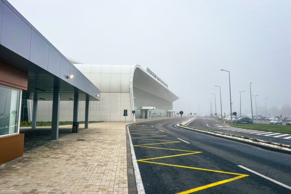 Modern airport terminal in Craiova, Romania, surrounded by mist, with a clear road layout and parking spots visible.