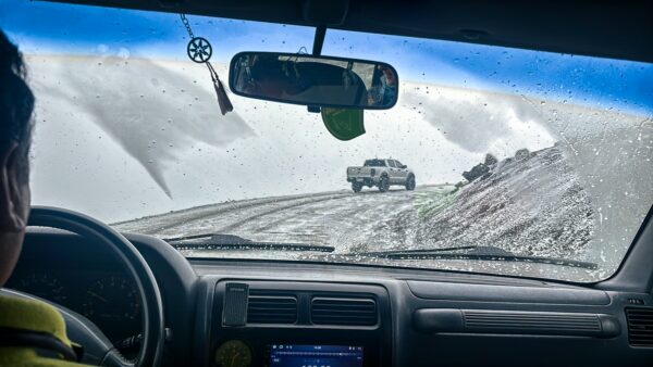 Chimborazo Volcano road view shows a snowy landscape and a truck navigating the winding path in Ecuador.