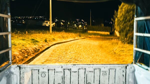 Cobblestone road illuminated by streetlights, framed by greenery, leading through La Esperanza at night in Ibarra, Ecuador.