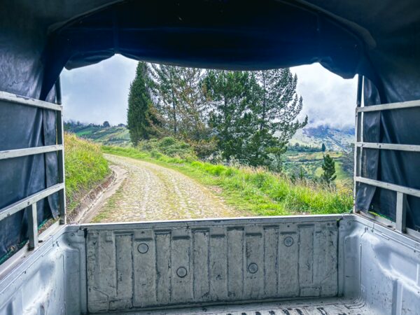 Rustic truck view overlooking a winding dirt road surrounded by lush greenery in La Esperanza, Ibarra, Ecuador.