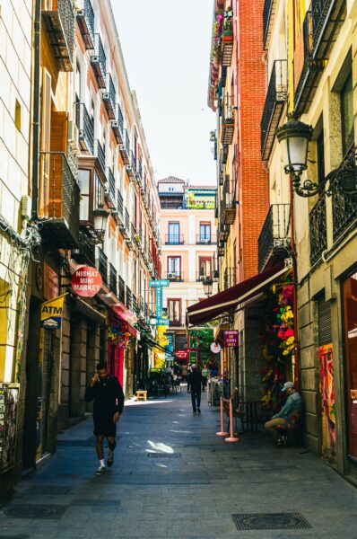 Charming narrow street in Madrid, Spain, lined with colorful shop awnings and vibrant decorations, inviting a leisurely stroll.