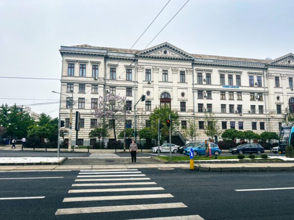 Elegant architecture and well-maintained gardens frame the University of Craiova, set against a cloudy sky in Romania.